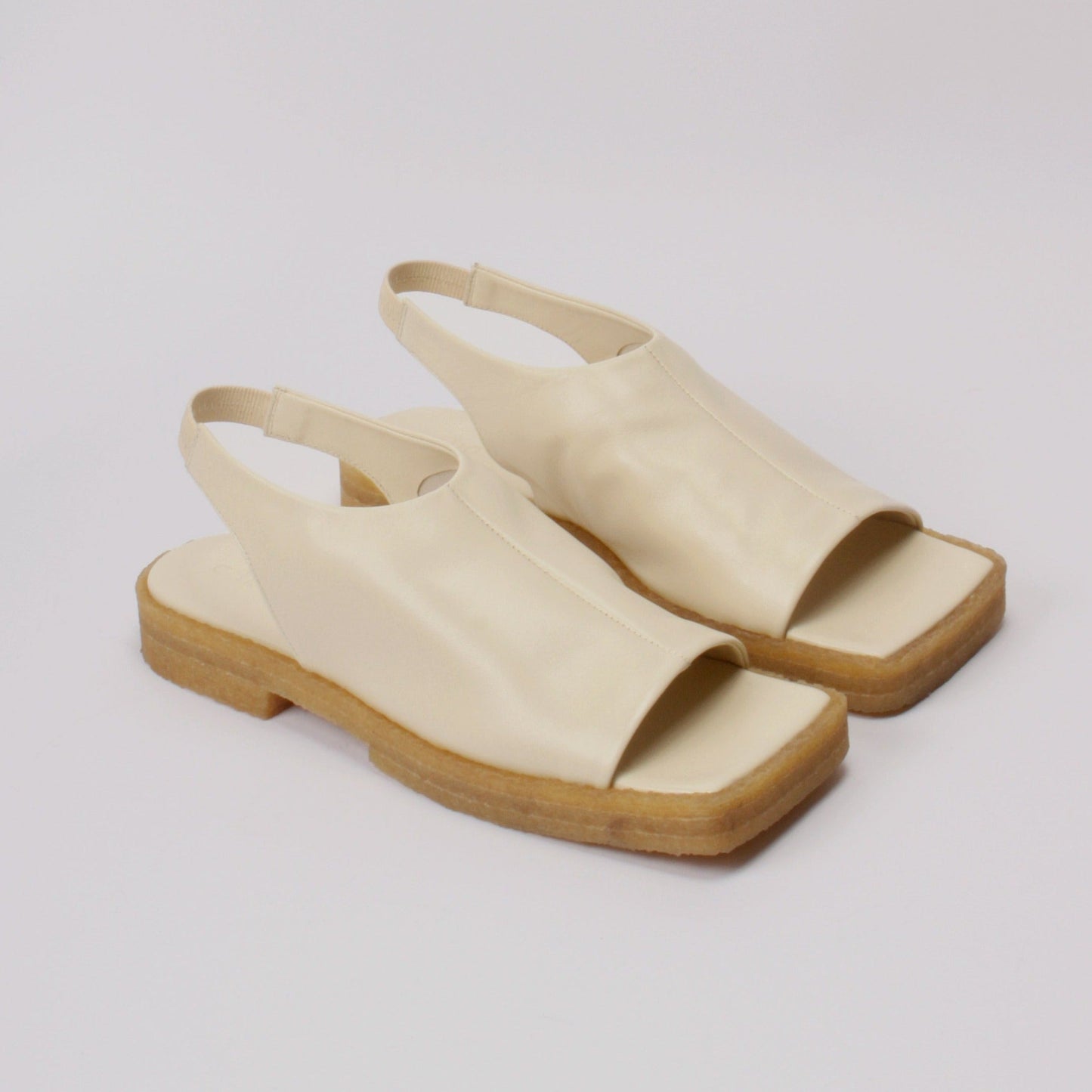 Unlined block platform sling-back sandals made of cream coloured lamb leather with a subtle shiny finish