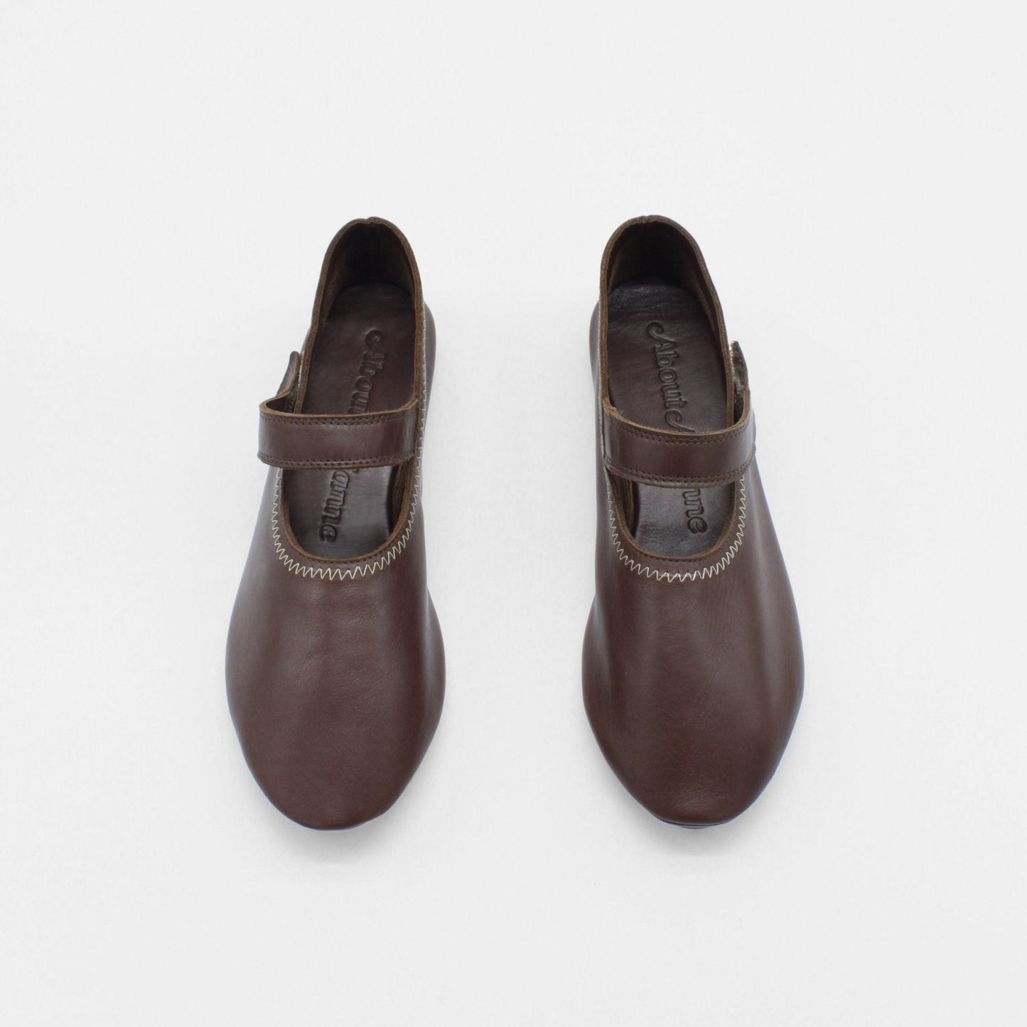 Unlined flat mary-jane made of dark brown lamb nappa leather with a shiny finish and stitching details.