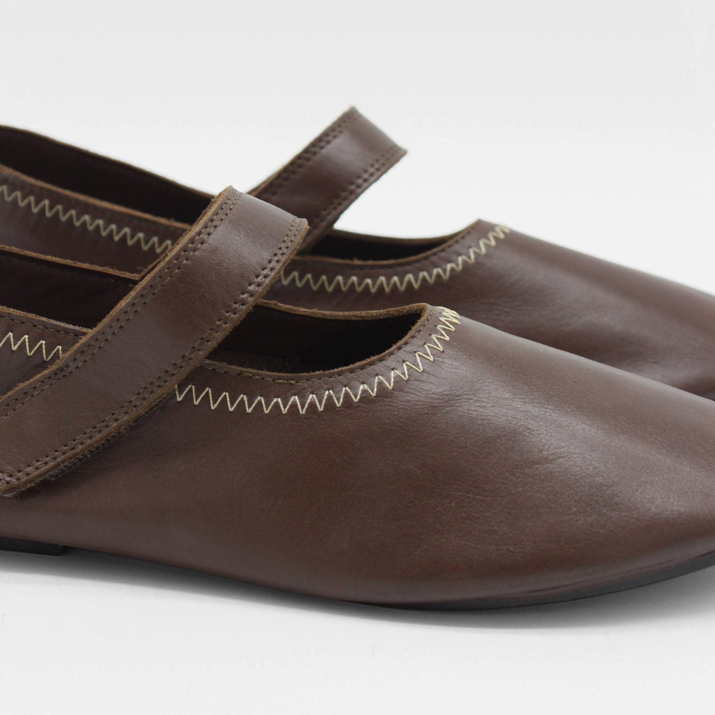 Unlined flat mary-jane made of dark brown lamb nappa leather with a shiny finish and stitching details.