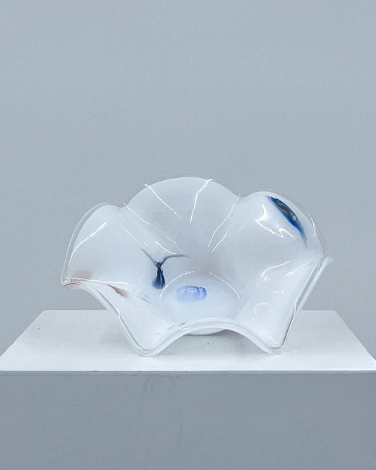 Glass sculpture on a white pedestal against a gray background