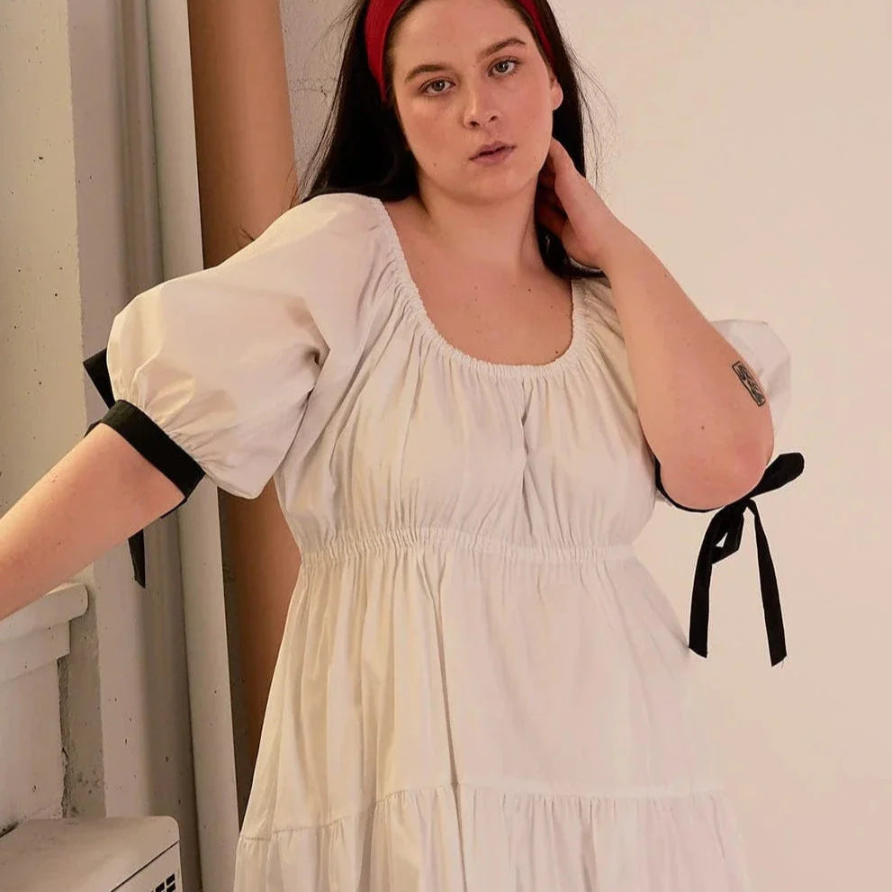 Overall white dress with extra puffy sleeves, gathered tiers, and black bow-tie details, the Jolen dress is both elegant and incredibly comfortable too. It's fully lined with cotton, slips on easily over head, and has pockets.