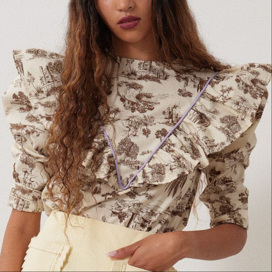 brown Toile de Jouy with bold lilac piping and matching grosgrain ribbon to really make it pop. The leg-o-mutton puff sleeves are lined with tulle for maximum volume. 100% Cotton. Slips on over head and ties in a bow at the back neck