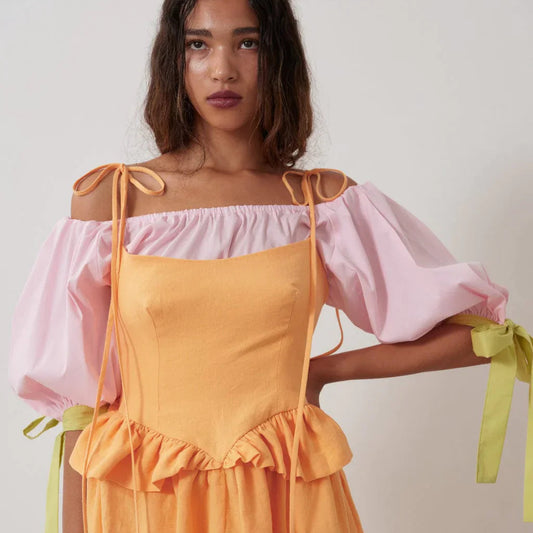 The sally top is pink with full puff sleeves that sit above the elbow with the help of big, bold adjustable green ties and an elasticized neckline so you can wear it on or off the shoulder.