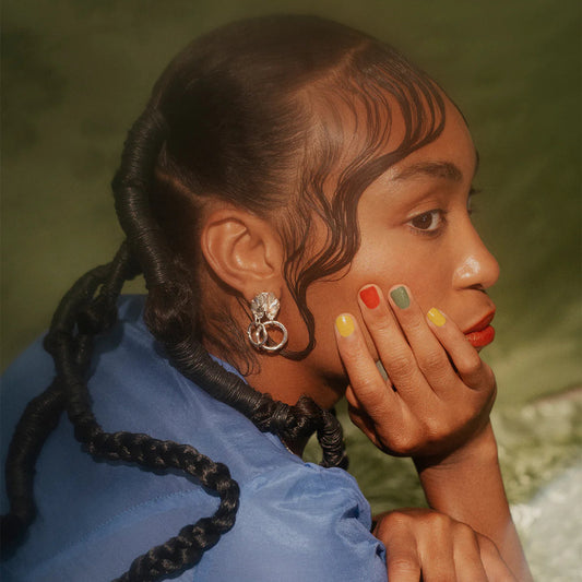 Woman with braided hair wearing a blue top against a blurred natural background