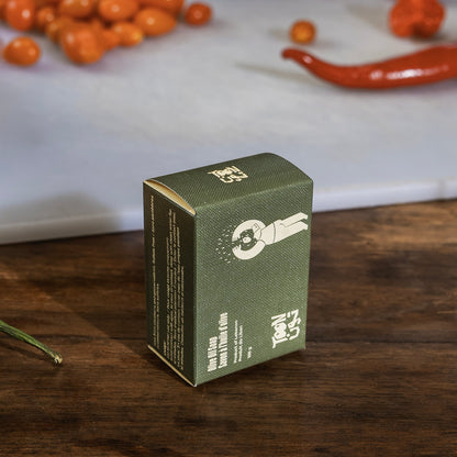 Green skincare product box on a wooden surface with berries and a white cloth in the background