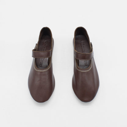 Unlined flat mary-jane made of dark brown lamb nappa leather with a shiny finish and stitching details. 
