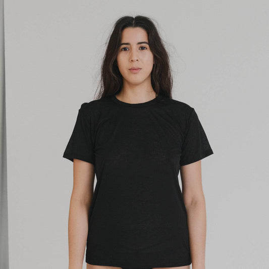 Person wearing a black t-shirt and black underwear against a plain background