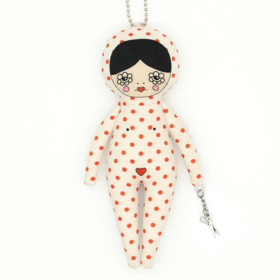 Keychain in the shape of a doll with polka dot pattern on a white background