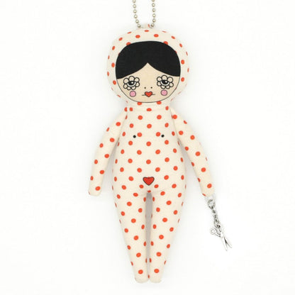 Keychain in the shape of a doll with polka dot pattern on a white background