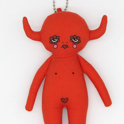 Red plush toy with facial features and a heart on a white background