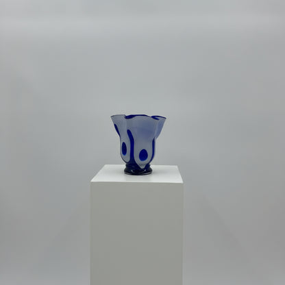 Blue glass object with white base on a gray background