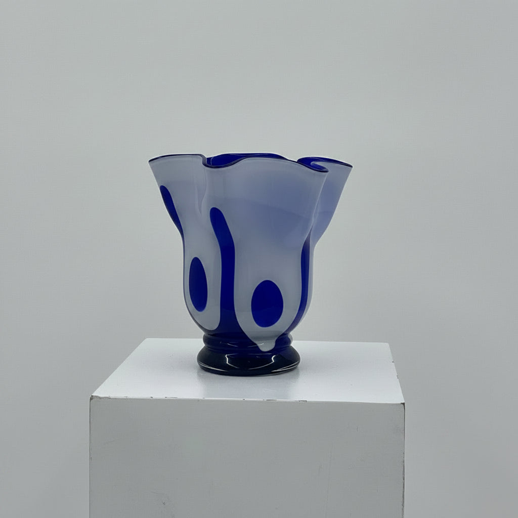 Blue glass vase on a white pedestal against a gray background