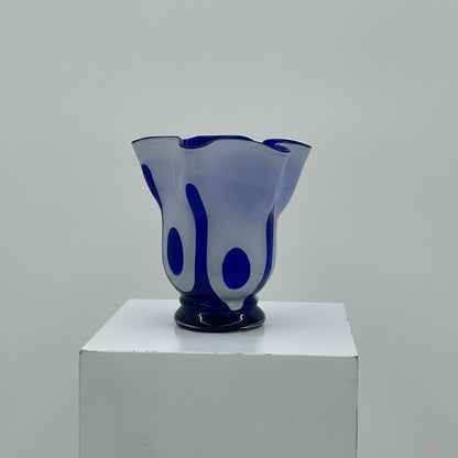 Blue glass vase on a white pedestal against a gray background
