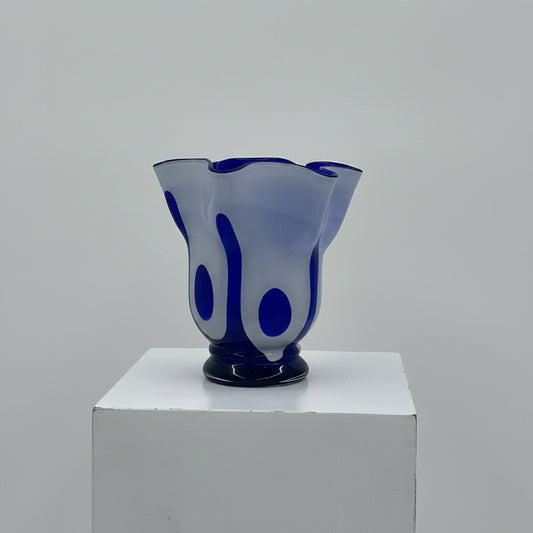 Blue glass vase on a white pedestal against a gray background
