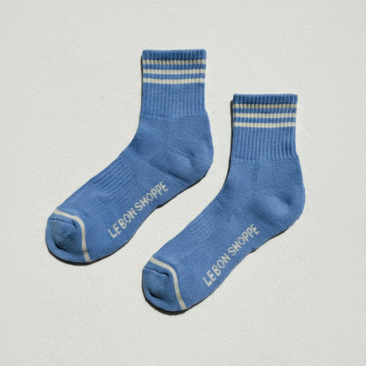 Pair of blue socks with striped pattern and 'LE BON SHOPPE' branding on a light gray background