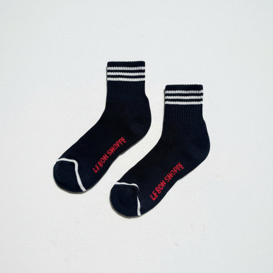 Pair of black socks with off white stripes and red text on a light gray background