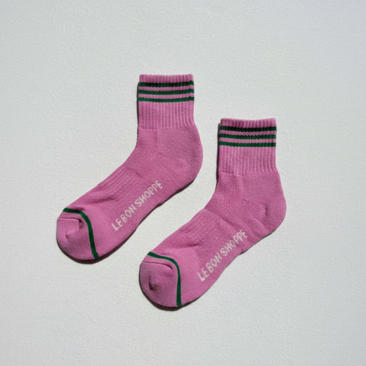 Pink socks with black and green stripes on a light gray background