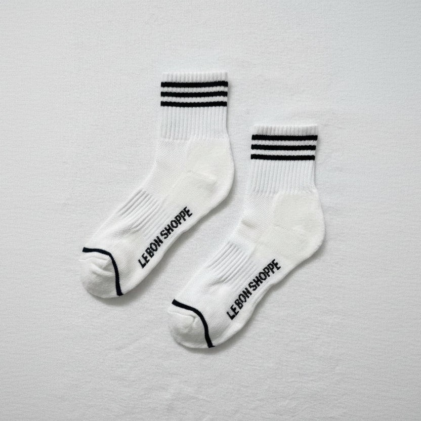 White socks with black stripes and 'Le Bon Shoppe' text on a light gray background