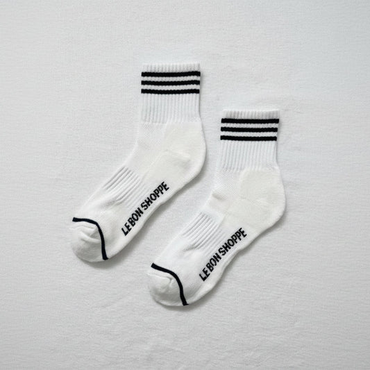 White socks with black stripes and 'Le Bon Shoppe' text on a light gray background