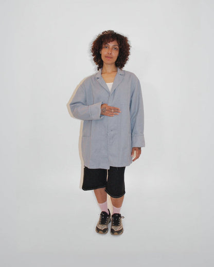 Person wearing a light gray coat on a white background