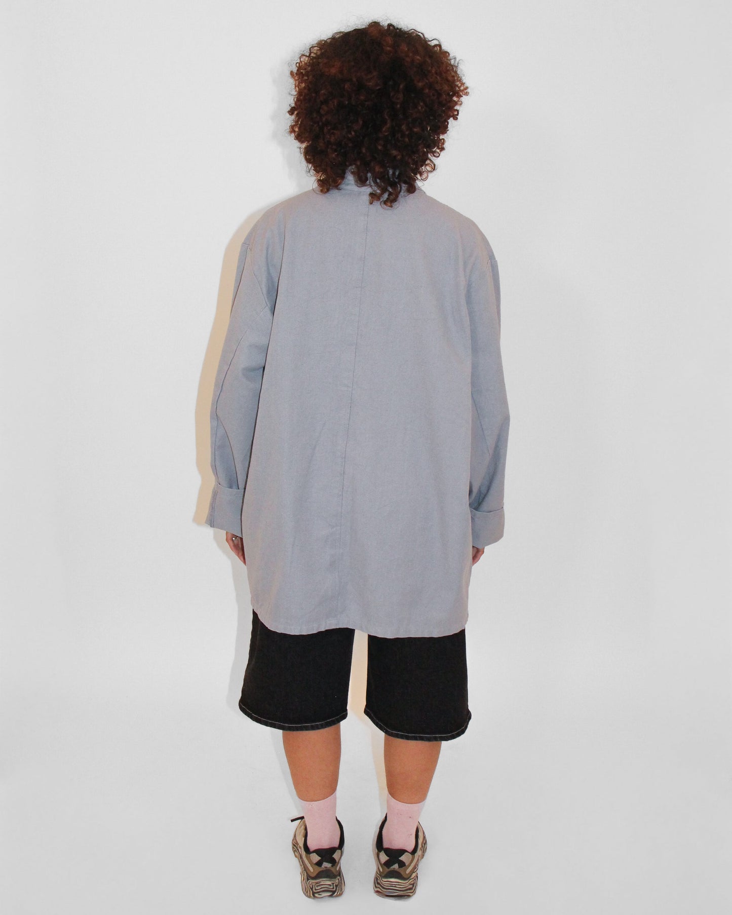 Person wearing a long, light gray dress with a subtle pattern on a white background