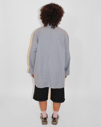 Person wearing a long, light gray dress with a subtle pattern on a white background