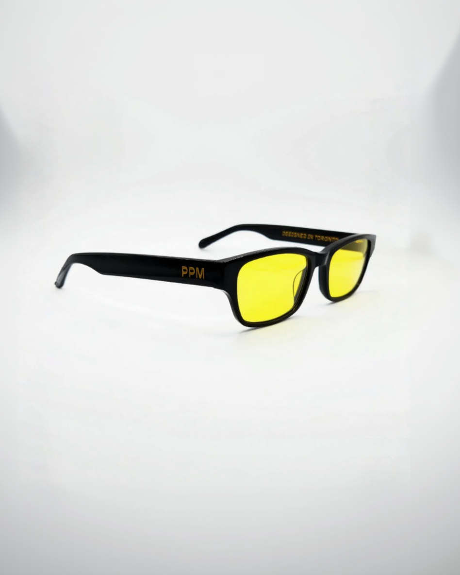 Black-framed sunglasses with yellow lenses on a white background