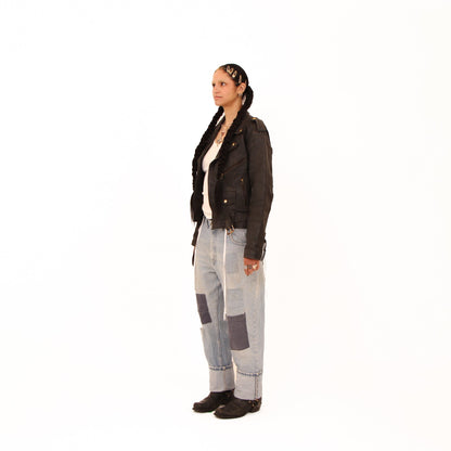 Person wearing a black jacket and patterned pants on a white background